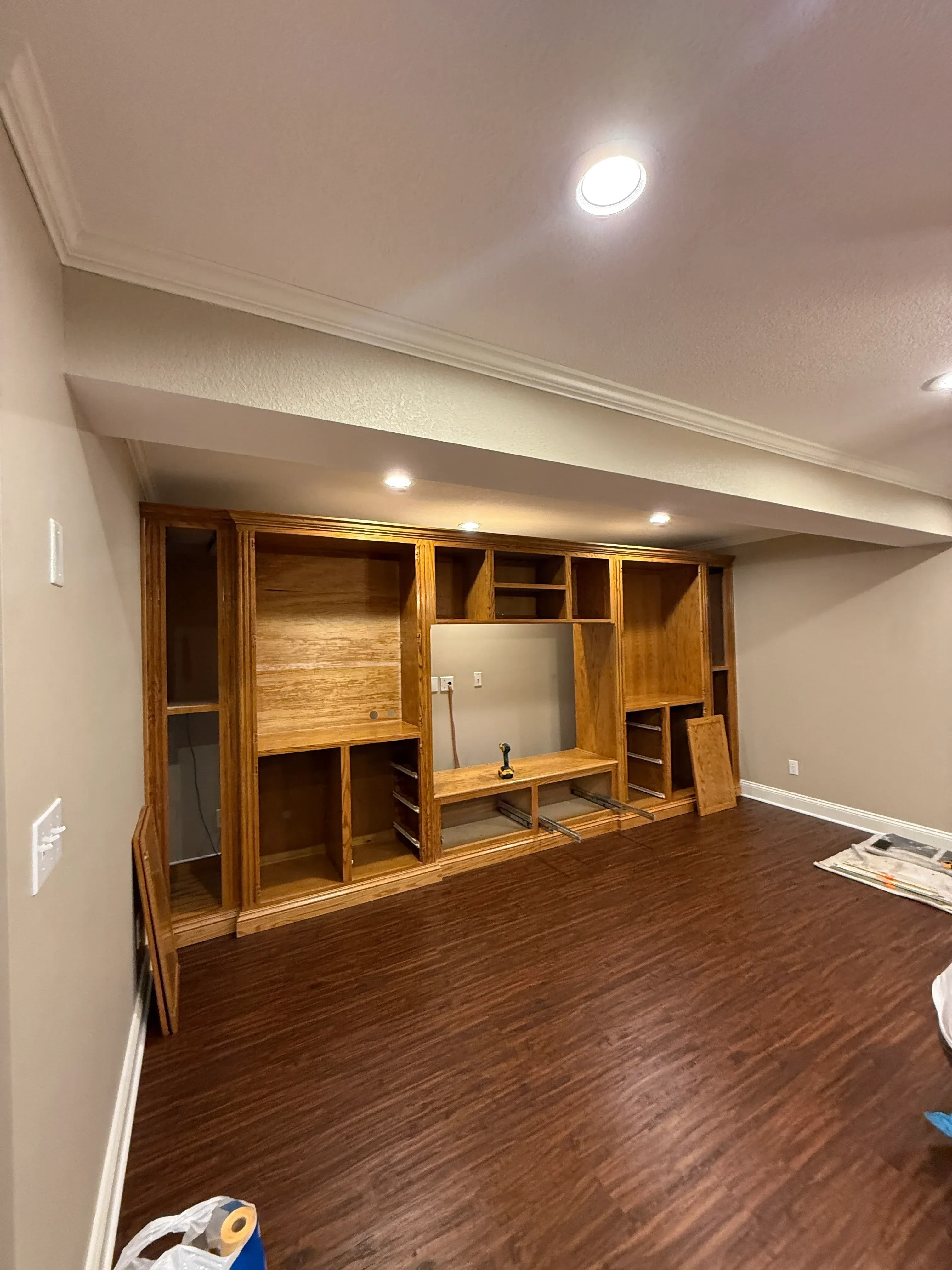 Freshly painted interior walls with white trim, recessed lighting, and wood shelving unit