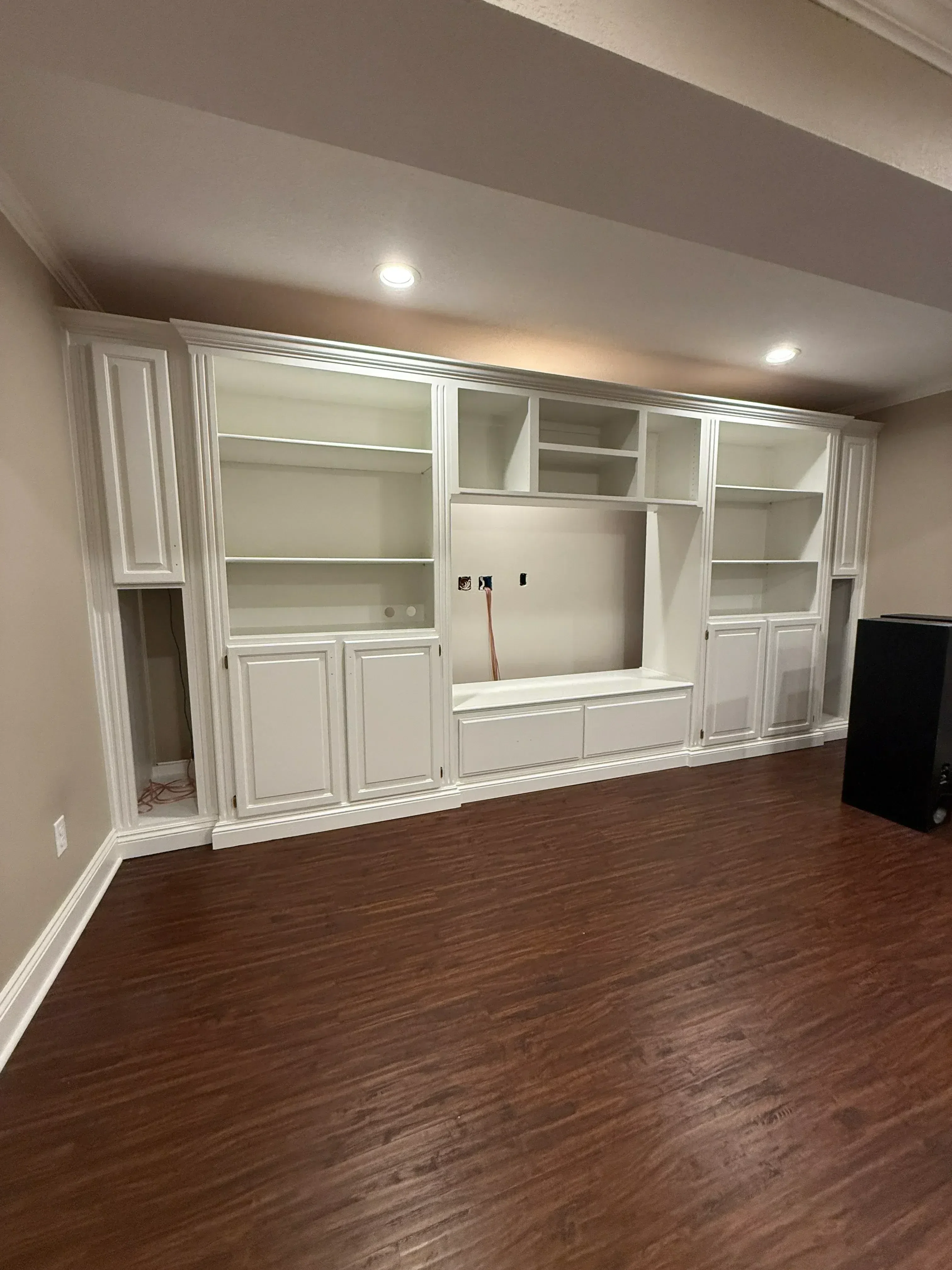 White built-in shelving with glass display cases, solid doors, and recessed lighting in residential interior